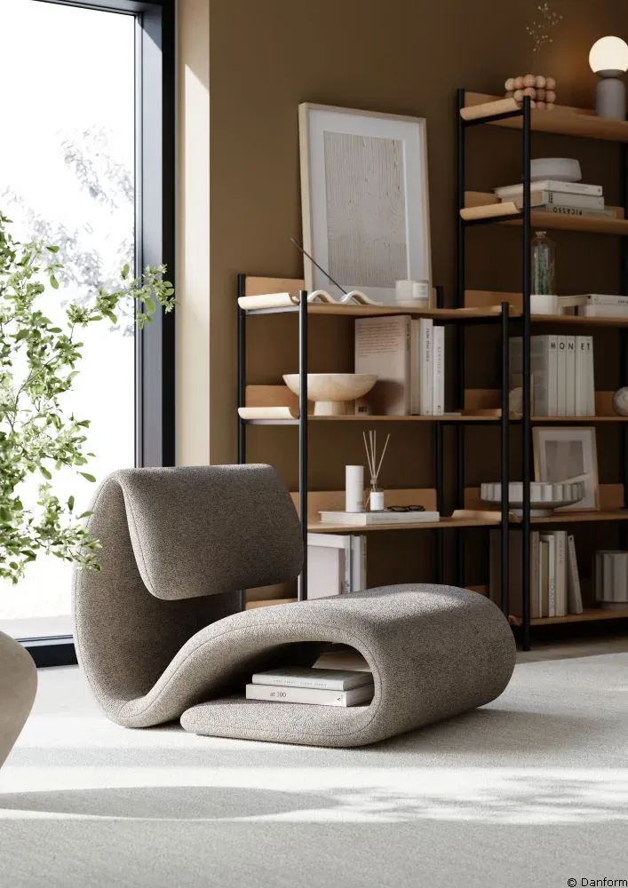 Geschwungener Lounge-Sessel von Dan Form vor einem Bücherregal