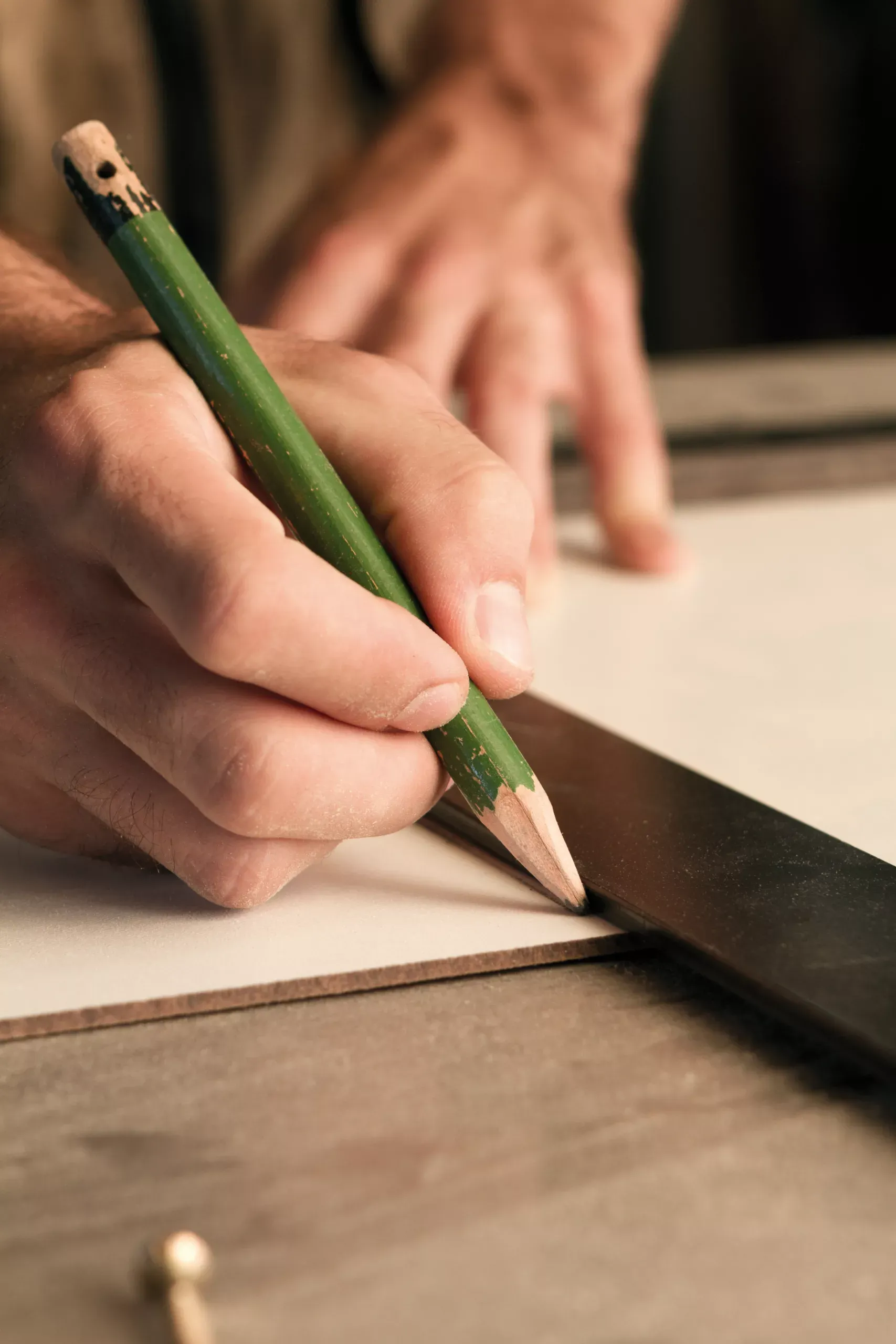 Hand mit Zimmermannsbleistift zeichnet auf ein Brett