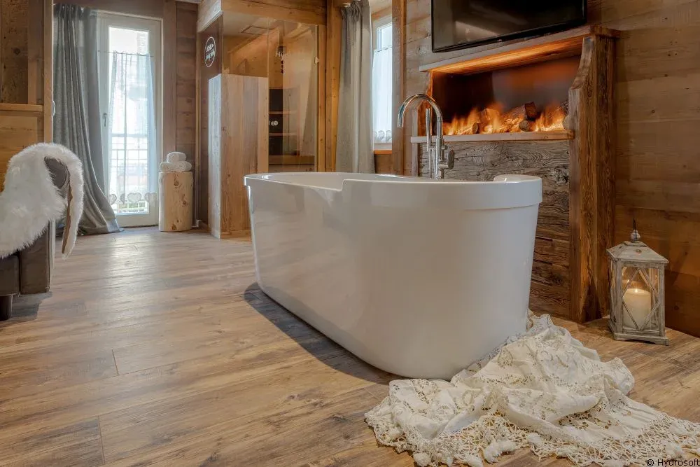 Badezimmer mit freistehender Wanne, Altholz und Kamin